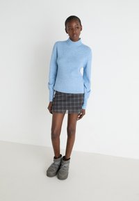 Svetlo modra rebrasta turtleneck pulover, črna karirana mini krila z valovitim robom in sivi čeveljski čevlji z obloženim gležnjem ter vzorčastimi vezalkami.