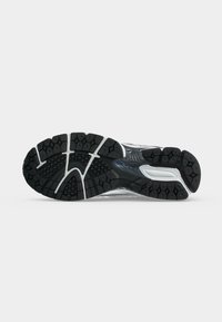 Ασπρόμαυρη σόλα με πέλμα ενός παπουτσιού New Balance για τρέξιμο, με υφή λαβής και ορατό όνομα της μάρκας.
