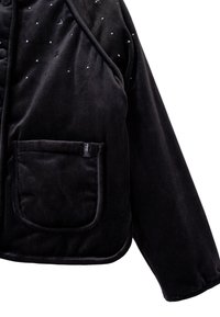 Giacca in velluto nero con un colletto rotondo, tessuto testurizzato, una tasca a toppa e piccole decorazioni decorative sulla superficie.