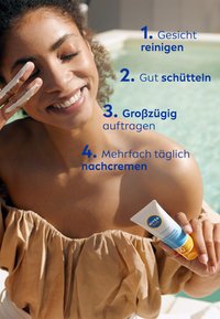 Sonnencreme-Tube mit blauen und orangefarbenen Akzenten, aus weißem Kunststoffmaterial. Eine Person trägt Sonnencreme auf und lächelt in der Nähe eines Pools. Weiche, beige Stoffoberfläche.