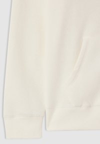 Manica di felpa color avorio e polsino a coste con tasca a marsupio frontale visibile su uno sfondo grigio chiaro.
