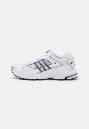 Biały sportowy sneaker z szarymi paskami, panelami z siateczki i teksturowaną podeszwą, pokazany z boku na jednolitym jasnym tle.