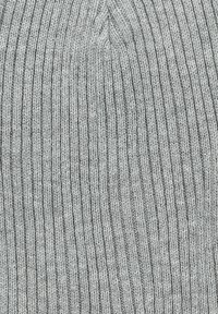 Szara robiona na drutach czapka z dzianiny z teksturą prążkowaną, z pionowymi liniami i bezszwowymi szwami na czubku. Materiał wydaje się być miękki i elastyczny.