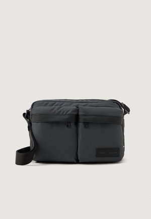 Black nylon messenger bag with dual front pockets, adjustable shoulder strap, leather accents, and a branded tag. Smooth texture and rectangular shape.