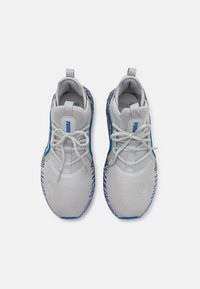 White athletic shoes featuring a breathable mesh upper with blue and navy zigzag accents, round toe, and white laces.