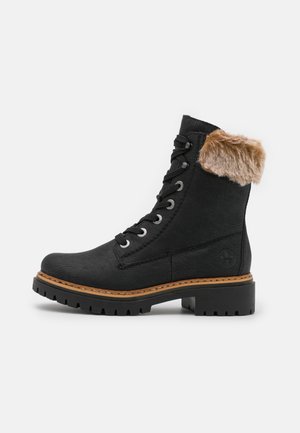 Bottine noire à lacets avec bordure en fourrure marron, semelle robuste et semelle intermédiaire cousue beige, vue de profil sur fond blanc.