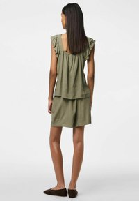 Top verde oliva, dal taglio ampio con maniche a volant, abbinato a pantaloni corti coordinati. Entrambi sono realizzati in un tessuto leggero e testurizzato.