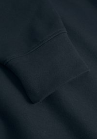 Navy blue sweatshirt cuff with a ribbed texture and double-stitched seams, highlighting a soft, stretchy fabric.