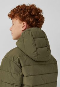 Puffjacke in Olivgrün mit einem gesteppten Design, einer eng anliegenden Kapuze und sichtbaren Nähten. Der Stoff wirkt glatt mit matter Oberfläche.