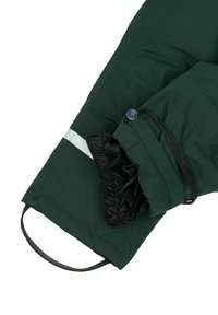 Manga de chaqueta impermeable verde con forro interior negro. Cuenta con puño elástico, detalle de botón y una tira reflectante a lo largo del brazo.