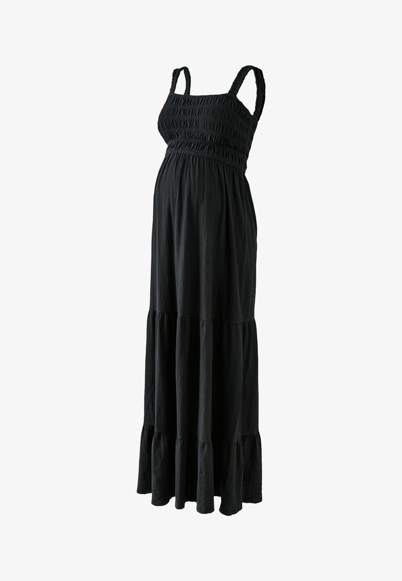 Robe maxi de maternité noire sans manches avec corsage smocké et jupe à volants sur fond blanc.