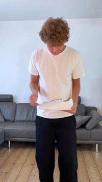Valged tennises jalanes, millel on sile tekstuur, ümar varvas, lame tald ja nööride aksendid. Kame seljas lihtne valge t-särk ja mustad püksid.