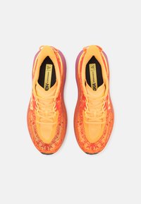 Chaussures Hoka Speedgoat 6 en maille orange vif et jaune avec des détails texturés et une semelle extérieure violette ; dotées d'un col rembourré et de lacets.