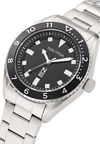 Reloj de pulsera Nautica de metal plateado con esfera negra, marcadores de hora blancos, bisel giratorio y tres manecillas que marcan las 11:13:40.