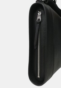 Czarna skórzana torba o teksturowanej powierzchni, z metalowym zamkiem i detalami w kolorze srebrnym. Zaokrąglony dół i regulowany pasek zapewniają wszechstronność.