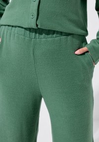Pantalons de loungewear en polaire verte avec une taille élastique, des poches latérales et une finition lisse.