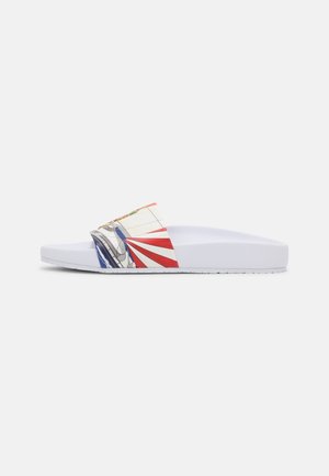 White slide sandal with a patterned strap in red, blue, and yellow graphic designs; features a textured footbed and flexible sole.