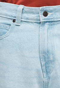 Φωτεινά μπλε τζιν παντελόνια με ίσια γραμμή, διαθέτουν κούμπωμα με κουμπί, μπροστινές τσέπες και εμφανείς λεπτομέρειες ραφής.