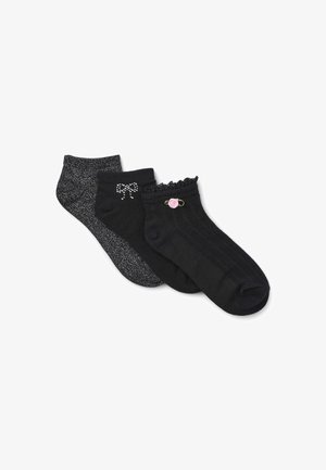 Tre paia di calzini neri: uno con un design a fiocco scintillante, uno con un polsino arricciato e un accento floreale, e uno con un motivo testurizzato solido.