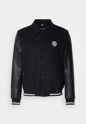 Black varsity jacket with wool body and leather sleeves. Features a tiger emblem on the left chest and striped ribbed cuffs and hem.