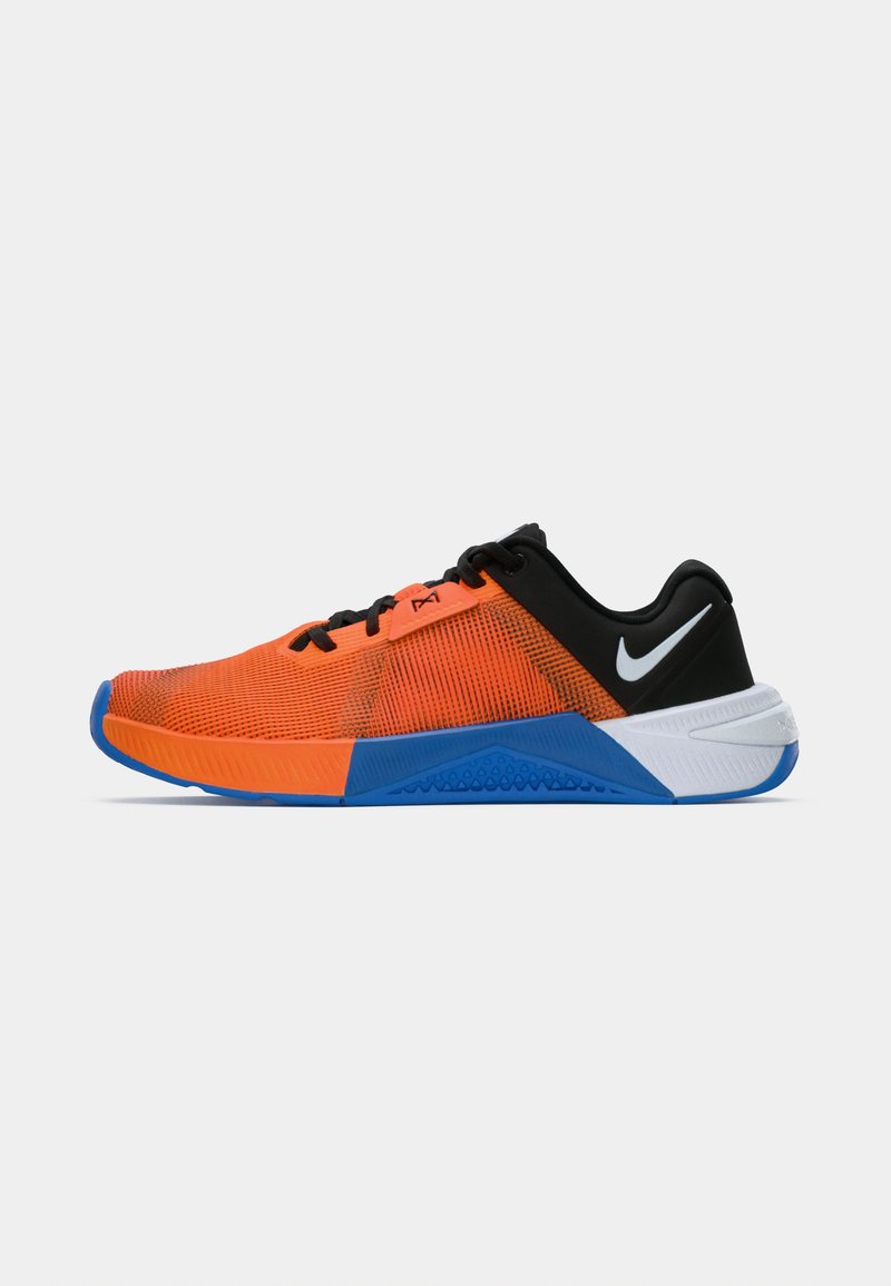 Zapato deportivo para hombre con parte superior de malla naranja, talón negro, suela azul y blanca, cordones negros y logo de Nike en blanco en el talón.