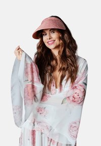 Półprzezroczysty strój w kwiatowy wzór z szerokimi rękawami i warstwową teksturą. Kompletuje go różowa słomkowa daszek.
