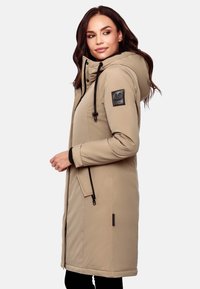 Beige outerwear jacket with a hood, zippers, black accents, and a smooth texture. Features logo patch on the left sleeve and side pockets.