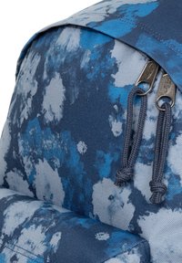 Zaino in tessuto blu e grigio con una trama caratterizzata da un motivo floreale, dotato di doppie zip e chiusura a patta.