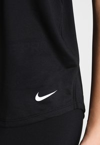 Top atletico nero realizzato in tessuto liscio, con un logo Nike bianco vicino all'orlo, dotato di un design aderente e dettagli di cucitura eleganti.