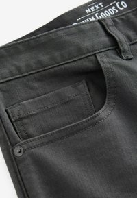 Pantaloni din denim negru cu un design clasic, dotati cu un buzunar frontal pentru monede, o textura fina si detalii subtile de cusaturi.
