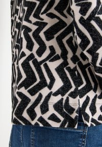 Strickpullover mit einem schwarzen und cremefarbenen Zickzackmuster, einer weichen Textur und einem leicht verkürzten Schnitt am Saum.