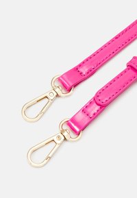 Deux sangles synthétiques rose vif avec boucles pivotantes en métal doré sur un fond clair.