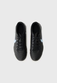 Black soccer shoes featuring a textured surface, black laces, and a light blue swoosh logo on the side, with a rounded toe design.
