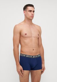 Boxeri scurți de culoare bleu marin, cu un brâu negru pe care este inscriptionat "justcavalli" în alb. Realizați dintr-un material neted și elastic.