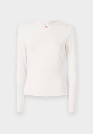 Camisola branca de manga longa, com nervuras, gola redonda, bainha desfiada e um subtil accent floral junto à gola. Tecido suave e texturizado.