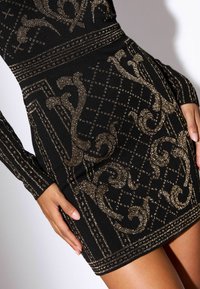 Rochie negre cu mâneci lungi, cu modele de sclipici auriu și designuri geometrice. Fabricată dintr-un material elastic, cu o siluetă ajustată.