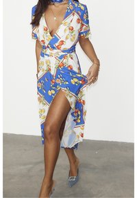 Robe portefeuille bleu et blanche à motif floral avec des manches courtes, présentant une fente haute sur la cuisse, une taille cintrée et un motif de fruits colorés.