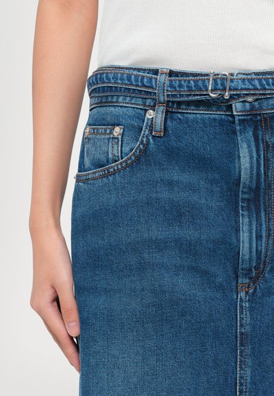 Denim krilo v srednjem modrem pranju, z oblikovano pasico z zankami za pas, detajli sprednjih žepov in kontrastnim šivanjem. Gladka tekstura.