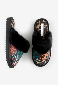 Faux fur slide slippers featuring a patchwork design with floral and geometric patterns on a black background and textured black sole.