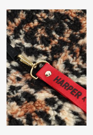 Zwarte rits op een multicolore wolstof met een rode stoftrekker gelabeld "HARPER & YVE" en een gouden metalen ritslider.