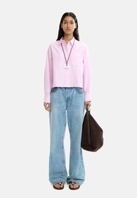 Różowa w paski koszula z guzikami, jasnoniebieskie dżinsy o wysokim stanie, brązowa torba na ramię, czarne klapki, naszyjnik z zawieszką, prosty krój, swobodny styl.