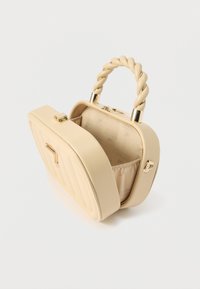 Bézs színű táska steppelt mintával, csavart fogantyúval, arany színű fém díszítéssel és tágas belső térrel, amely mintás szövettel bélelt.