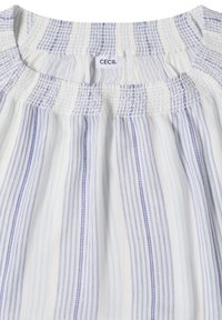 Blouse blanche à rayures violet clair avec col smocké et une petite étiquette portant la mention "CECIL" à l'intérieur du col.