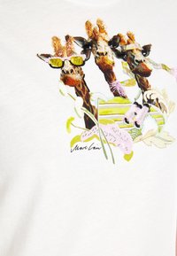 Weißes Baumwoll-T-Shirt mit einer gestickten Grafik von drei Giraffen, die Sonnenbrillen tragen, ergänzt durch florale Akzente und bunte Stickdetails.