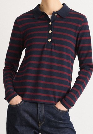 Marineblaue und burgunderrote gestreifte Langarm-Polohemd mit Kragen, drei Knöpfen und lockerem Schnitt, kombiniert mit dunkelblauen Jeans.