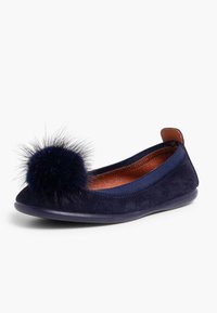 Ballerine en suède marine avec un pompon en fourrure rond sur le bout. Dotée d'un bord élastique et d'une semelle en caoutchouc flexible. L'intérieur est en cuir beige.