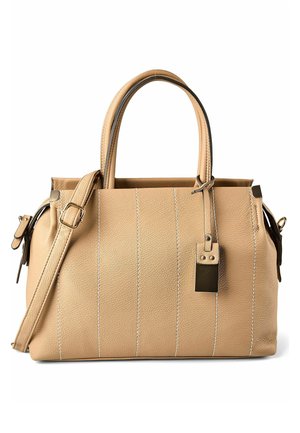 Borsa in pelle beige con doppi manici, tracolla regolabile, cuciture verticali e una targhetta metallica rettangolare appesa.