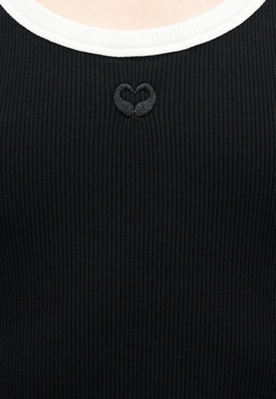 Μαύρο ριγωτό υφαντό τοπ με λευκή λαιμόκοψη και μικρή κεντημένη μαύρη καρδιά στο κέντρο του στήθους.