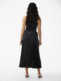 Saia midi preta plissada com uma textura suave e faixa na cintura, combinada com um top preto justo sem mangas e sandálias de salto.