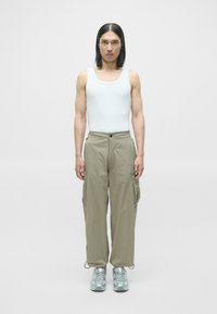 Lyseblå tanktop, beige cargo-bukser med lommer og lysegrå sneakers. Outfittet har en afslappet pasform og et enkelt design.